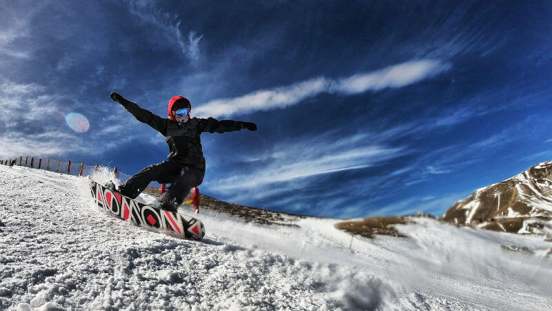 Deslizándose con estilo y confianza por la montaña nevada, una persona demuestra su habilidad y pasión por el snowboard en un emocionante descenso invernal.